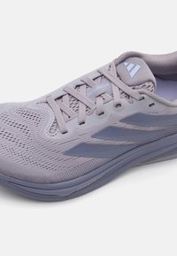 Paarse sportschoenen met een ademende mesh bovenkant, gestructureerde details en drie donkerblauwe strepen aan de zijkant. Licht gevoerde zool.