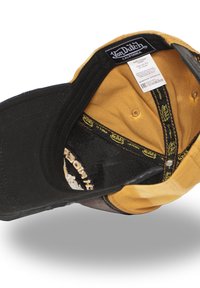 Gorra negra y amarilla con visera curvada, que presenta una etiqueta de logo negra en el interior y un forro texturizado. Las costuras interiores están bien terminadas.