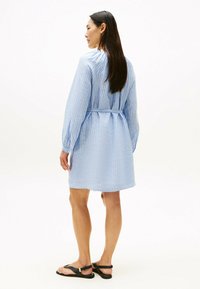 Blå og hvide stribet kjole med lange ærmer og bindebælte i taljen. Fremstillet i let materiale med afslappet pasform og rynket halsudskæring.