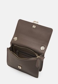 Borsa a mano in pelle marrone con un design strutturato, hardware dorato, una chiusura magnetica quadrata e una tasca con zip all'interno.