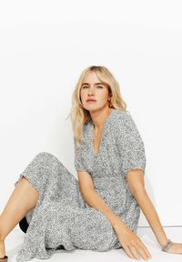 Robe midi noire et blanche à pois avec des manches courtes bouffantes, un décolleté en V et une taille froncée, fabriquée en tissu léger.