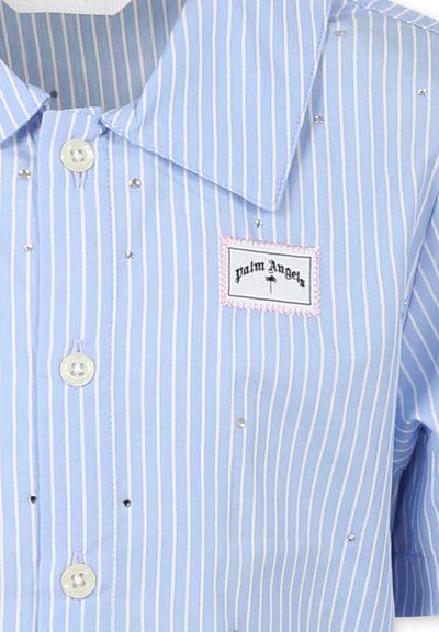 Camicia a righe blu chiaro realizzata in un tessuto con una texture liscia. Presenta un colletto a punta, chiusura con bottoni e piccoli ornamenti decorativi.