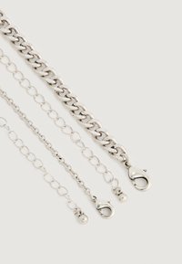 Kolm hõbedast kettapikendit, millel on homaariklipid ja väikesed pallikestad, esitatud lihtsa heleda taustaga.