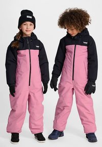 Dwoje dzieci nosi różowe i czarne ocieplane kombinezony zimowe z kapturem, rękawicami oraz zamkiem błyskawicznym z przodu na jednolitym tle.