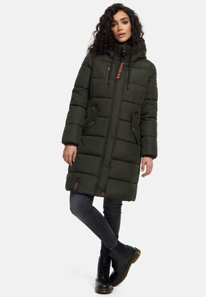 Green puffer coat with a hood, featuring two front pockets, drawstrings, and brown accents; paired with dark gray skinny jeans and black boots.