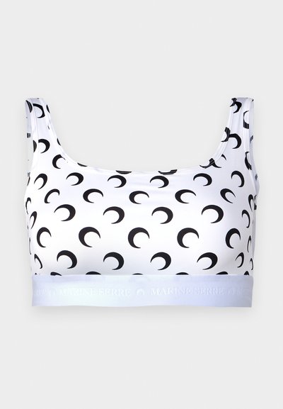 Bílý top s krátkým rukávem má černý vzor půlměsíce, elastickou tkaninu, široké ramínka a elastický pás s brandingem "MARINE SERRE".