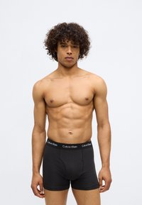 Black boxer briefs with a soft elastic waistband featuring the "Calvin Klein" logo. Smooth fabric with a fitted design.