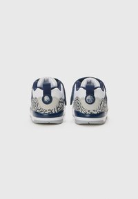 Sneaker mit weißem Grund, marineblauen Akzenten und grauem Tierdruck. Verfügt über einen gepolsterten Kragen, eine Ziehschlaufe an der Ferse und eine strukturierten Außensohle für besseren Halt.