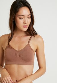 Brun bomull bralette med justerbare stropper, samlet midtpunkt detalj og en glatt tekstur. Designet for komfort og enkelhet.