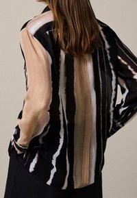 Silkeskjorte med et lodret stribet mønster i forskellige nuancer af sort, beige og brun, med en afslappet pasform og lange ærmer.