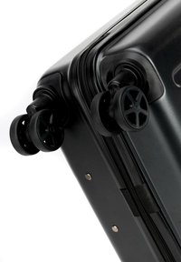 Valigia rigida nera con ruote girevoli doppie, chiusura con zip e rivetti in metallo. Texture liscia e design elegante.