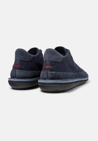 Navy blue suede and mesh sneakers feature a textured fabric with a rounded toe and a black rubber sole, accented by a red brand logo.