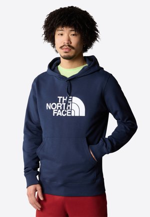 Sudadera con capucha azul marino hecha de una mezcla de algodón, con un gran logotipo blanco, capucha con cordón ajustable y un bolsillo tipo canguro en la parte frontal.