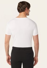 Witte getailleerde t-shirt met korte mouwen, een gladde textuur en een ronde hals, gecombineerd met zwarte broeken met achterzakken.
