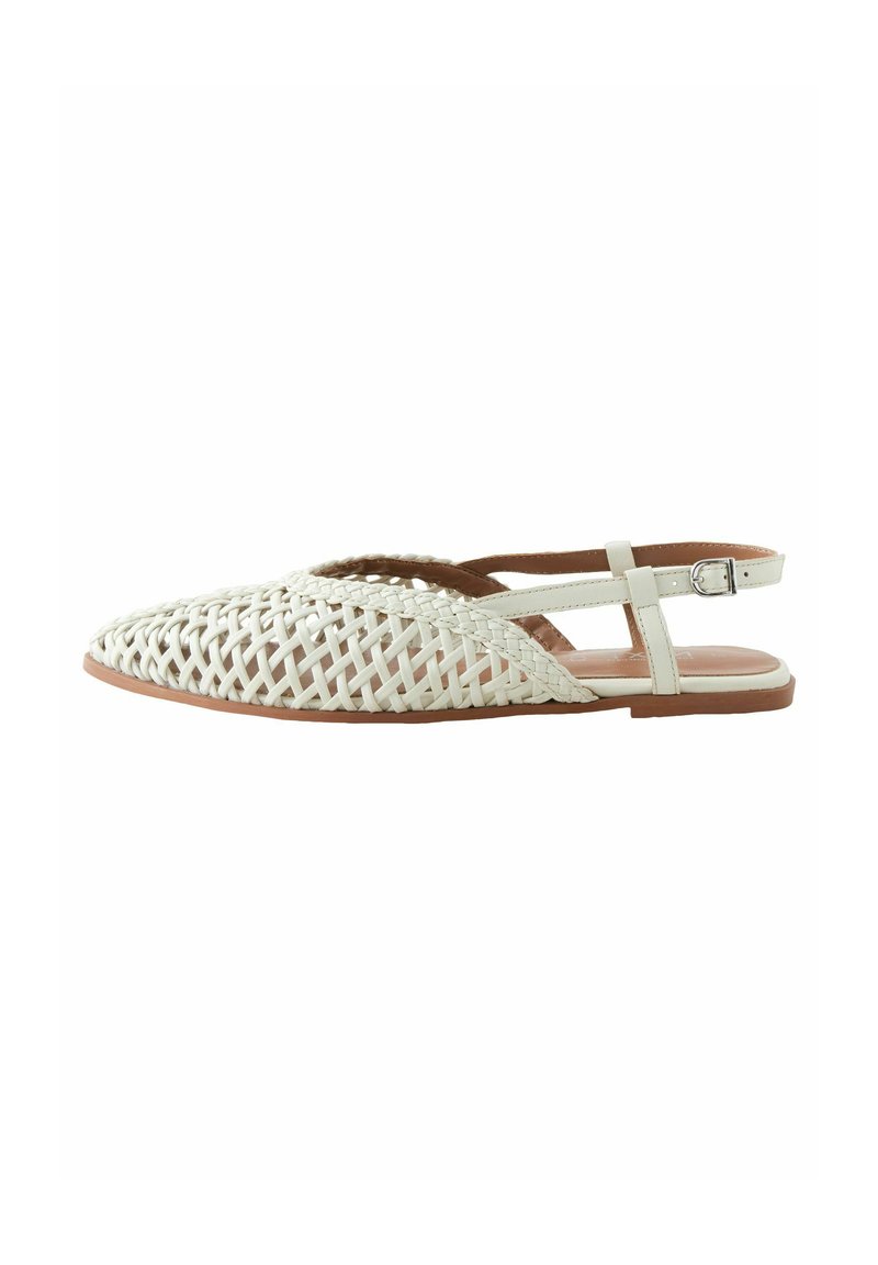 Sandale à talon ouvert et plat, tressée en matériau blanc, avec une semelle brun clair et une lanière de cheville avec un détail de boucle en argent.