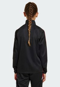 Schwarze Sportjacke mit hohem Kragen und langen Ärmeln, die eine glatte Textur und einen subtilen roten Akzent entlang der Schulternaht hat.