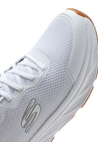 White athletic shoe with a mesh upper, textured finish, and subtle silver accents. Features a rubber sole and lace-up design.