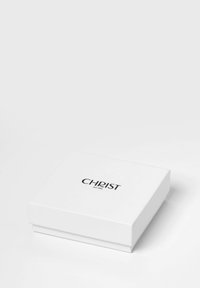 Weißer Geschenkkarton mit glatter Oberfläche, auf dessen Oberseite ein schwarzes, erhabenes Logo mit der Aufschrift "CHRIST est. 1863" zu sehen ist. Rechteckige Form.