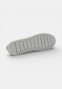 Suela de zapato con banda de rodadura de goma blanca, con ranuras verticales y patrones triangulares para tracción, mostrada sobre un fondo blanco liso.