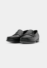 Schwarze Lederloafer mit einem Mokassin-Design, das eine gestickte Zehe und eine flache Sohle aufweist. Glatte Textur, minimalistischer Stil und keine sichtbaren Beschläge.