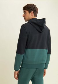 Felpa con cappuccio nera e teal, caratterizzata da un design a blocchi di colore, realizzata in un tessuto morbido con polsini e orlo a costine.