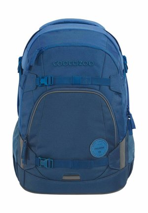 Blauem Rucksack aus strapazierfähigem Stoff, mit mehreren Reißverschlusstaschen, verstellbaren Trägern und einem runden Logo-Abzeichen auf der Vorderseite.