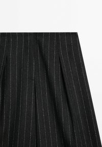 Black pinstripe fabric with subtle silver threading, featuring pleated detailing. Smooth texture, tailored design, and structured shape.
