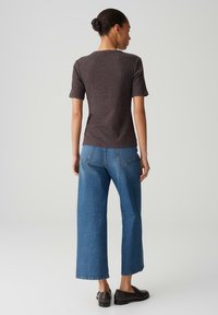 Brown ribbed short-sleeve top paired with wide-leg blue jeans. The jeans feature two back pockets and a straight cut at the hem.
