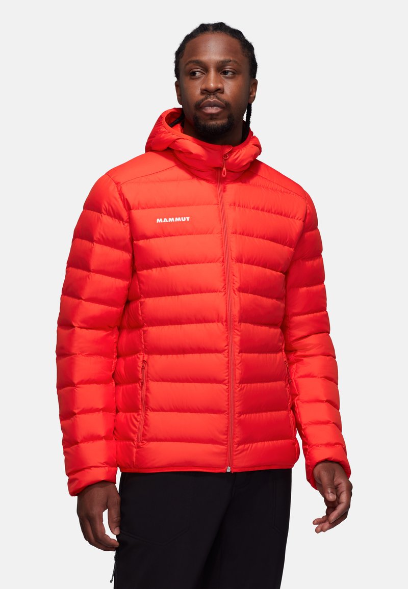 Rød pufferjakke med vandret quiltet design, lynlås foran og hætte. Har "MAMMUT" logo og to sidelommer.