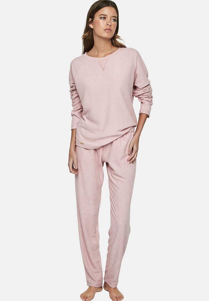 Lichtroze loungewear set met een langslavend top met een ronde hals en sweats met een elastische tailleband en taps toelopende pijpen.