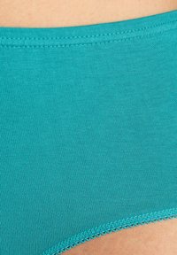 Tirkizno donje rublje od pamuka s rebrastom teksturom. Ima valoviti elastični pojas i glatku, bešavnu izradu.