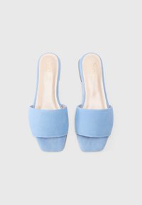 Mule in suede blu con una larga fascia davanti, punta aperta e tacco quadrato elegante. Fodera interna liscia con il nome del marchio inciso.