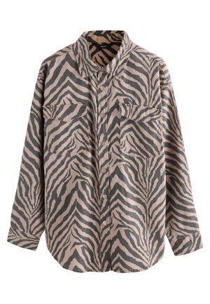 Long-sleeve shirt in a beige fabric with dark zebra stripes, featuring two front pockets, a collar, and button closure. Textured surface.
