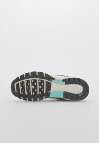 Nike athletic shoe outsole featuring black rubber with textured grip patterns, beige and light blue accents, and a logo engraved on the heel.