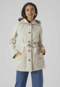 Manteau à capuche beige clair avec une ceinture, de gros boutons et des poches latérales. Tissu lisse avec une coupe décontractée et une capuche doublée.