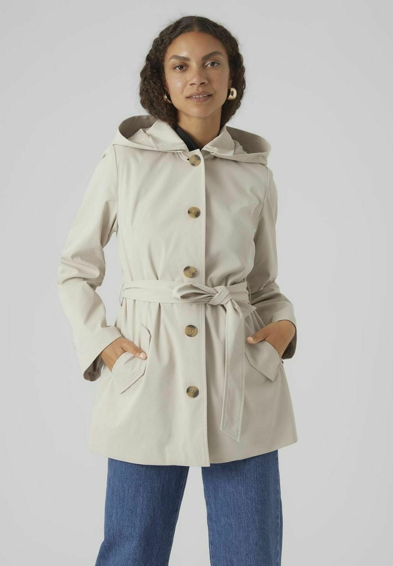 Manteau à capuche beige clair avec une ceinture, de gros boutons et des poches latérales. Tissu lisse avec une coupe décontractée et une capuche doublée.