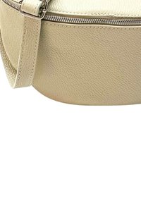 Ronde handtas van gestructureerd beige leer, met een zilveren metalen rits en een slanke schouderband, voorzien van een glad bovenstuk en een duurzame basis.