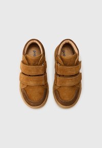 Brune suedesneakers med to justerbare velcro-remmer. Rund tådesign, gummisåle og sydd detaljer langs kantene.
