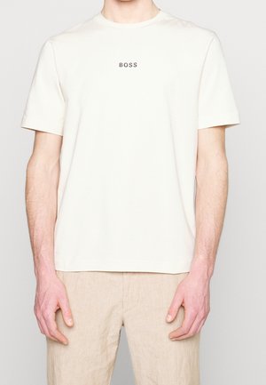 T-shirt di cotone color beige chiaro con scollo rotondo e maniche corte, con logo "BOSS" stampato in grigio scuro sul petto.
