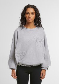 Gray sweatshirt with long sleeves, featuring embroidered butterfly designs on the front. Frayed hem and cuffs add texture.
