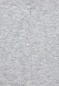 Pull en maille gris clair avec un col rond et une rangée verticale de cinq petits boutons brillants au centre.