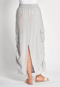 Hellgrauer Maxirock mit elastischem Bund, Seitentaschen und einem Oberschenkelschlitz. Hergestellt aus einem weichen, fließenden Stoff mit lockerer Passform.