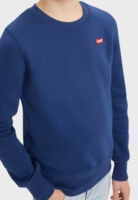 Felpa girocollo blu navy realizzata in tessuto morbido, con polsi e orlo a coste, e un piccolo logo rosso Levi's sul petto.