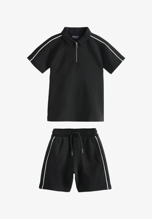 Cămașă polo neagră cu guler cu fermoar și dungi albe pe laterale, completată cu pantaloni scurți negri asortați, având un talie elastică și buzunare laterale.