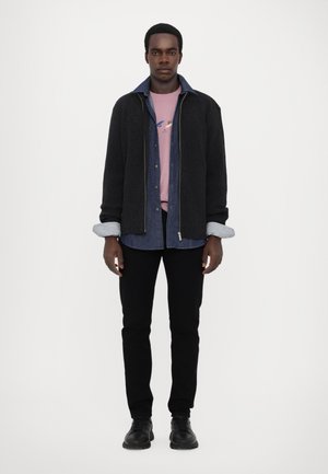 Svart ribbet cardigan med en denimskjorte under, rosa t-skjorte og svarte slim-fit bukser; svarte sko. Falmet denimskjorte med krage; sølvglidelås.