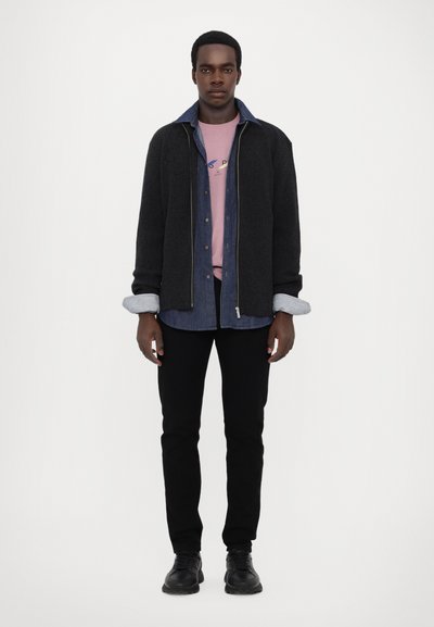 Černý žebrovaný cardigan s džínovou košilí pod ním, růžové tričko a černé slim-fit kalhoty; černé boty. Oblečení s vybledlým límcem džínové košile; stříbrný zip.
