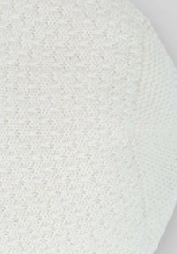 Cuscino rotondo bianco realizzato in un tessuto a maglia testurizzato con un motivo sottile. La superficie è morbida e leggermente piumosa.