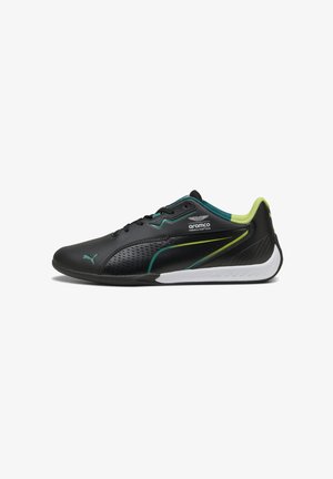 Fekete Puma sneaker törökzöld és lime színű kiegészítőkkel, fehér talppal, perforált oldallal és az Aramco Formula One Team logójával a külső oldalon.