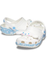 White clogs with blue cloud and bunny graphics, featuring a soft plastic material, ventilated design, and a strap for secure fit.