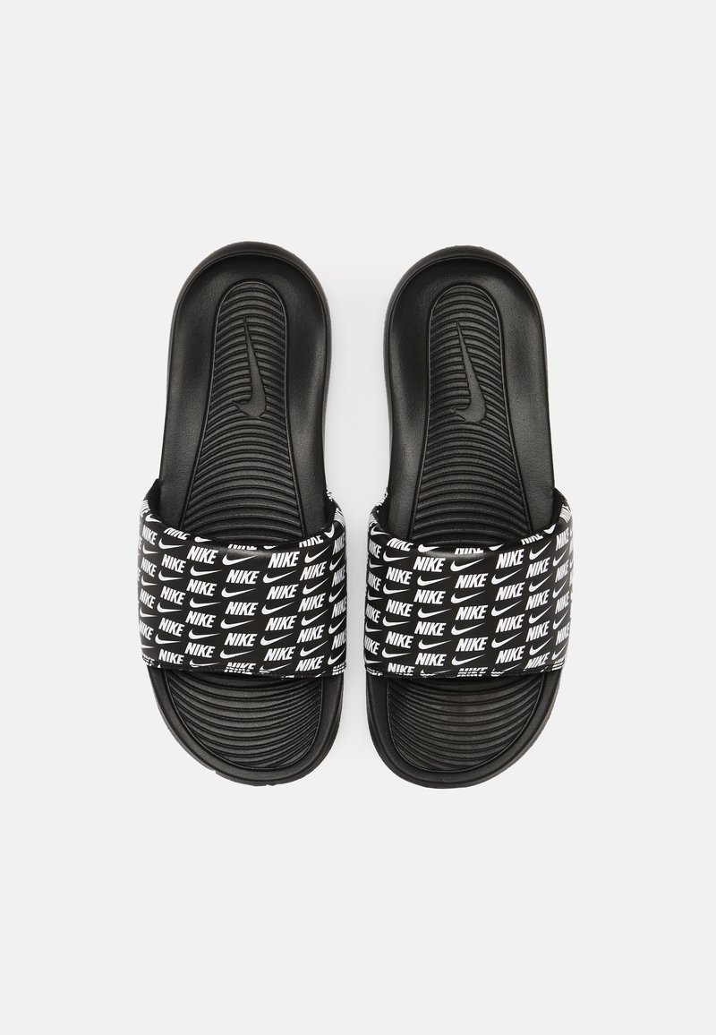 Chanclas negras con suela de espuma texturizada y una tira con logotipos de Nike en blanco repetidos en diferentes tamaños. Diseño abierto y plano.